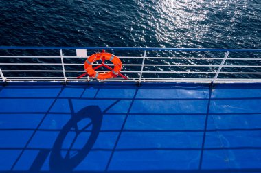 Akdeniz 'in önünde cankurtaranla birlikte beyaz korkuluk ve gölgesi yere düşüyor.