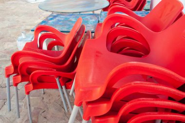 Dışarıdaki masaların yanına istiflenmiş kırmızı plastik sandalyeler. Coronavirus tarafından kapatılmış restoran işletmeleri