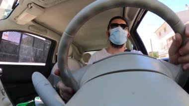 Campos, Balear Adaları / İspanya; Mayıs / 07 / 2020: Mavi maskeli ve güneş gözlüklü bir araba sürmek. Karantina zamanında sürüş