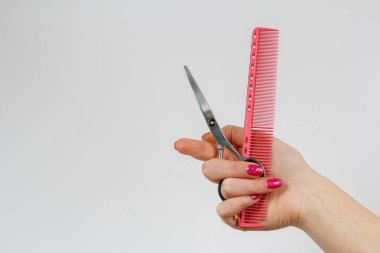 kadının elindeki makas ve pembe saç fırçası