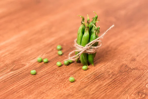 Guisantes verdes atados con cuerda sobre fondo de madera —  Fotos de Stock