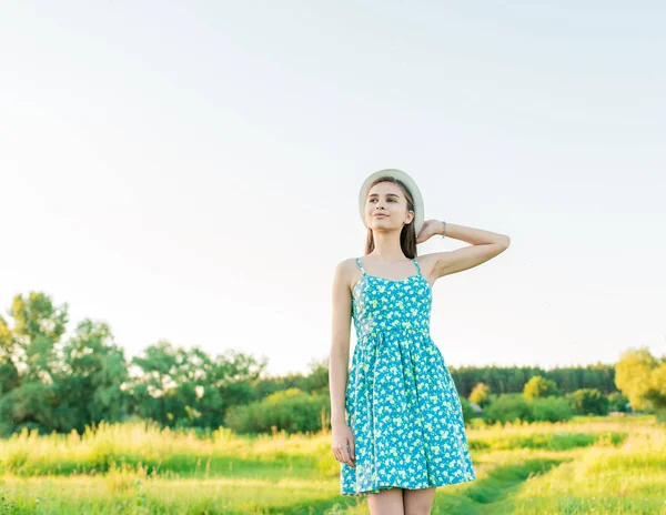 Een jong meisje in een blauwe jurk houdt een boek en een boeket van wilde bloemen in haar handen — Stockfoto