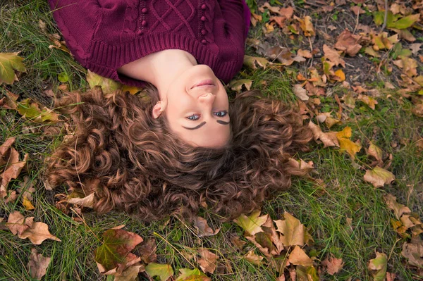 Молода усміхнена дівчина з листям в осінній час — стокове фото