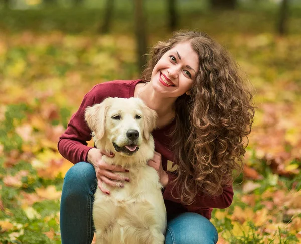 Gros plan de la femme bouclée assise avec son chien en automne laisse dehors — Photo