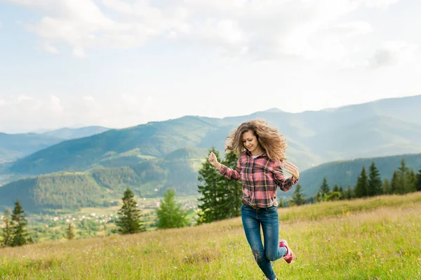 Mujer joven con el pelo largo mirando un paisaje de montaña —  Fotos de Stock