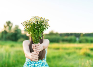 Kır çiçekleri buketi ile mavi elbiseli genç kız