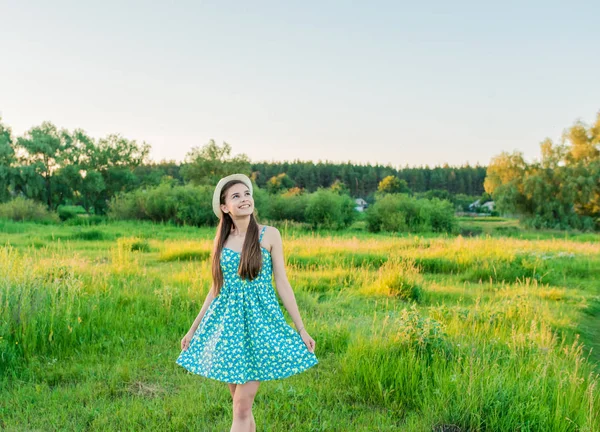 Meisje met een bos van chamomiles in een veld met hoog gras — Stockfoto