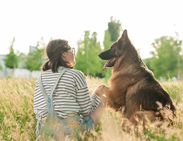 Jovem mulher e seu cão amigável em um parque — Fotografia de Stock