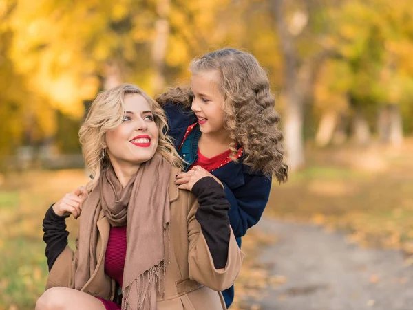 Feliz mujer alegre divirtiéndose con su chica en el color de otoño —  Fotos de Stock