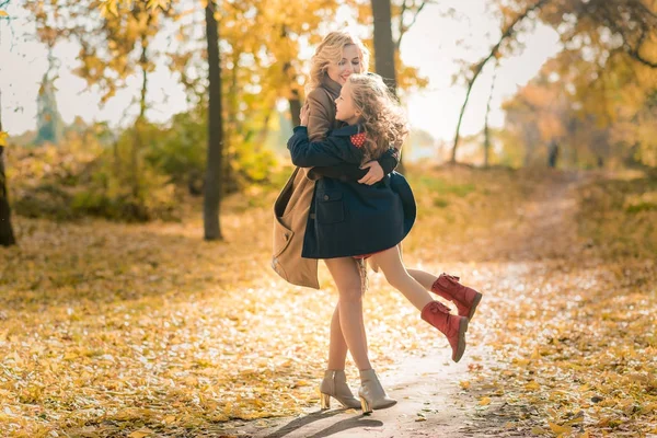 Gelukkig vreugdevolle vrouw plezier met haar meisje in herfst kleur — Stockfoto