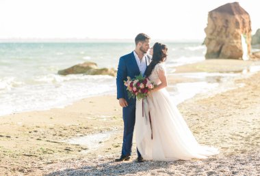 Düğün çifti, gelin ve damat deniz kenarında gelinlik giymişler.