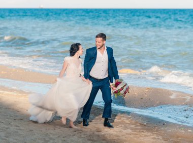 Düğün çifti, gelin ve damat deniz kenarında gelinlik giymişler.