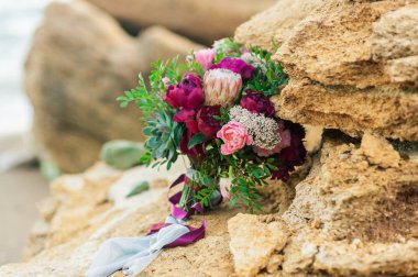 Taştaki kırmızı ve poz renklerle gelin buketi