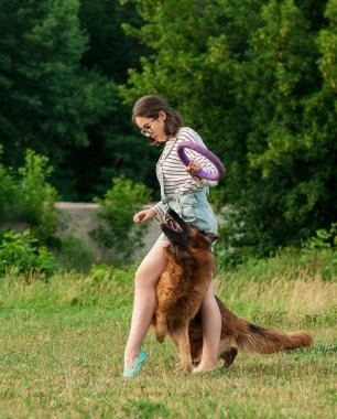 Genç bir kadın parkta köpeğiyle oynuyor.