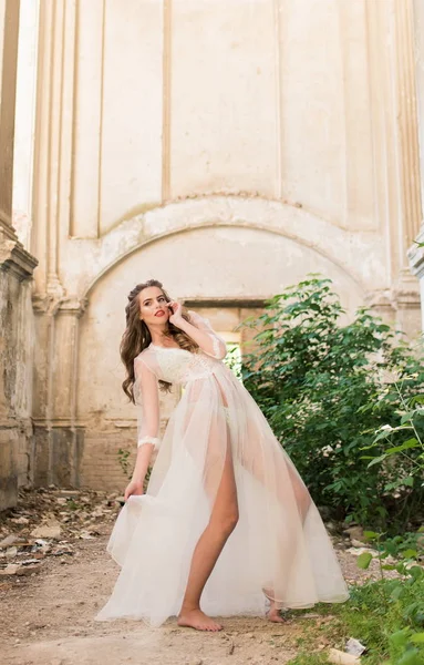 Portrait d'une jeune mariée en boudoir de dentelle blanche aux cheveux foncés ondulés — Photo