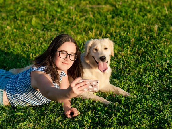 Jeune femme et son chien amical prendre un selfie dans un parc — Photo