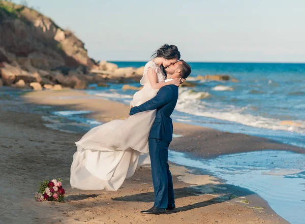 Düğün çifti. Güzel gelin ve damat. Sadece evlenmiş. Yakın çekim. Mutlu gelin ve damat onların düğün sarılma üzerinde. Damat ve gelin sahilde denize yakın. Gelinlik.