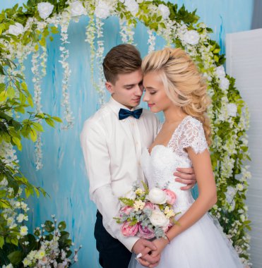 Düğün stüdyosu çekimleri, dekor öpücükler, sarılmalar. Mutlu bir çift. Lüks dekorasyonlu gelin ve damat aşıkları. Gelin ve damat birlikte. Çift kucaklaşması. Yeni evliler evleniyor.