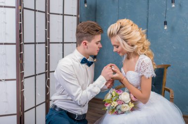 Gri bir stüdyoda el ele tutuşan güzel yeni evliler. Dantel bir elbise içinde gelin ve damadın portresi. Nazik bir düğün portresi..