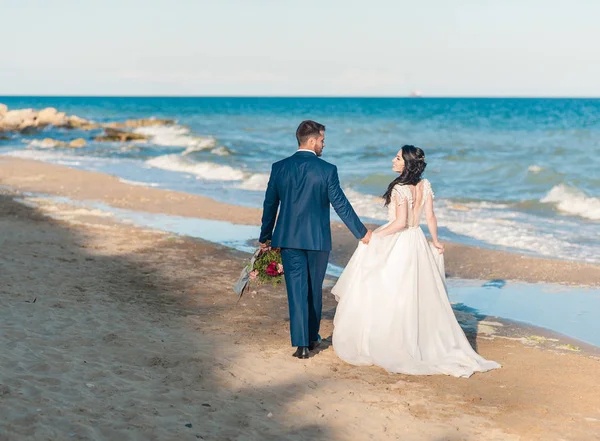 Pareja de boda, novio y novia en vestido de novia cerca del mar en la playa — Foto de Stock