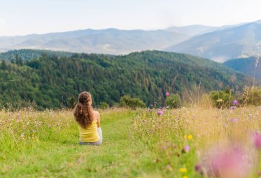 Spor kadın oturuyor ve dağların üstünde dinlenme seyahat. Dağlar manzara arka plan üzerinde.
