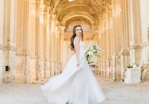 Romantiskt vacker brud i lyx klänning poserar för vackra arkitekturen Royaltyfria Stockfoton
