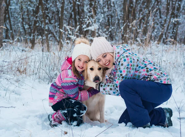 Familia abrazar a su mascota juntos en las vacaciones de Navidad en bosque congelado — Foto de Stock