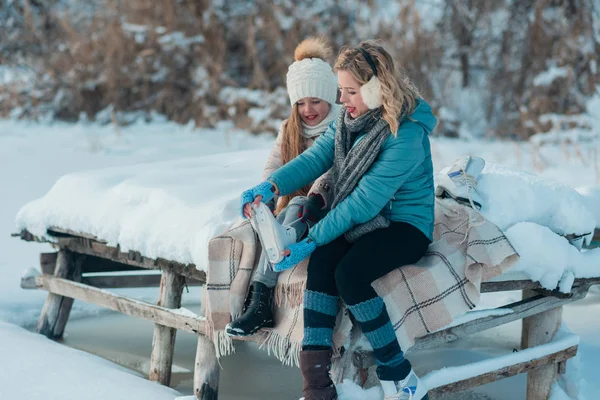 Rodina sedí na lavičce na břehu zamrzlého jezera. — Stock fotografie