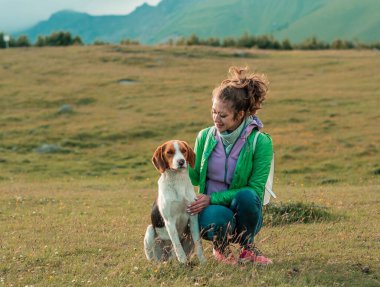Genç dişi ve köpek birlikte dağ manzarasının tadını çıkarıyorlar.