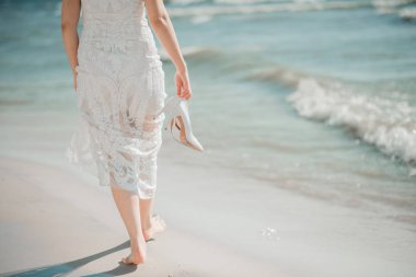 Gelin, düğün merasiminin olduğu yerin yakınında denizde yürüyor..