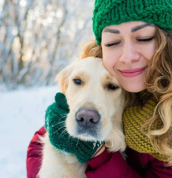 Yakın plan mutlu kadın sahibi ve kışın beyaz golden retriever köpeği.