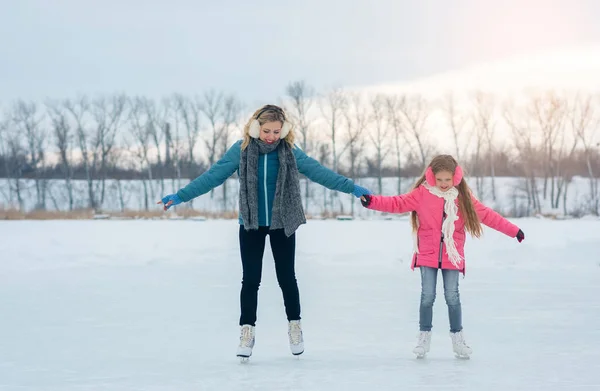 Familia joven divertirse en la zona de hielo en un parque cubierto de nieve —  Fotos de Stock