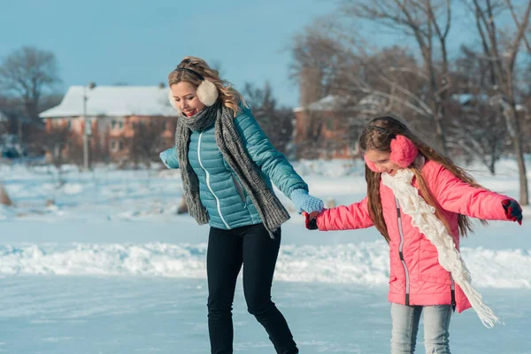 Familia joven divertirse en la zona de hielo en un parque cubierto de nieve —  Fotos de Stock