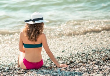 Genç kadın fotokopi odasıyla otururken renkli bikiniyle güneşleniyor..