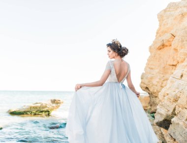 Açık şifonlu gelinlik içinde, deniz kenarında poz veren boncuklarla işlenmiş güzel esmer gelin. Sahilde poz veren lüks elbiseli romantik bir gelin..