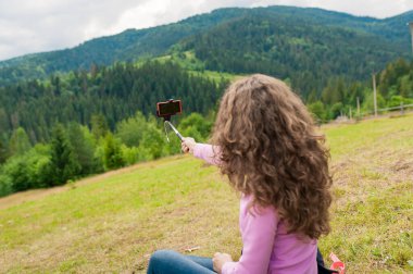 Neşeli kız konuşmak için akıllı telefonu kullanıyor. Dağlar tepesi. Yaz mevsiminde dağların güzel manzarası. İletişim konsepti