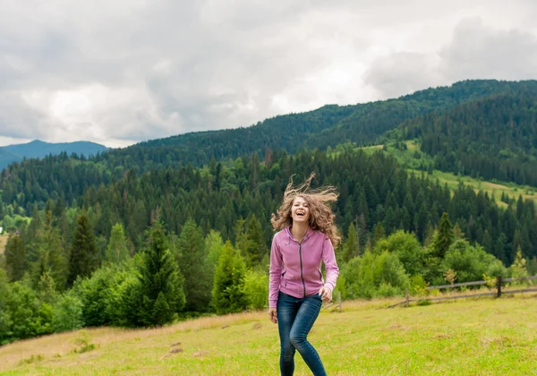 Curly woman on top peak of mountains in summer during holidays. Beautiful young female girl looking to camera. Young woman outdoors. Lifestyle concept.