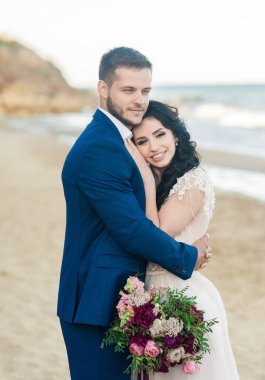 Düğün çifti, gelin ve damat deniz kenarında gelinlik giymişler.