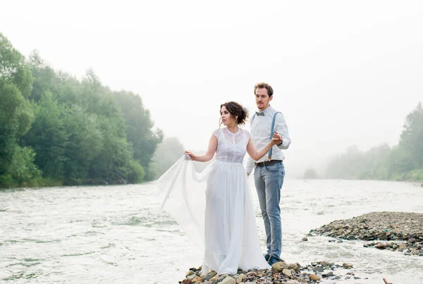 美しい風景の上に山の岩のヴィンテージスタイルの服を着て新婚夫婦 — ストック写真