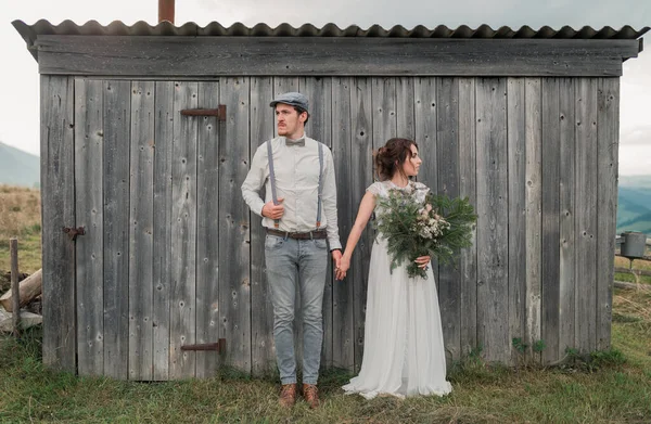 灰色の木製の壁の近くにヴィンテージスタイルの服を着た新婚夫婦 — ストック写真