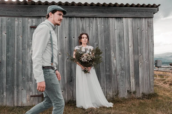 灰色の木製の壁の近くにヴィンテージスタイルの服を着た新婚夫婦 — ストック写真