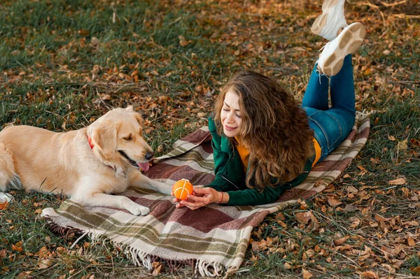Closeup of curly woman playing with her dog retriever in spring time season — Stock Photo, Image