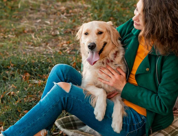 在公园里和她的狗一起玩黄金猎犬的年轻女人 — 图库照片