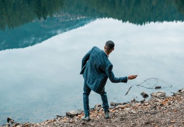 Zarif takım elbiseli, doğal arka planda yakışıklı Afro-Amerikan damat. Gelini bekleyen şık bir Afrikalı damat. Afrika düğün duygusal portresi. Damat gölde..