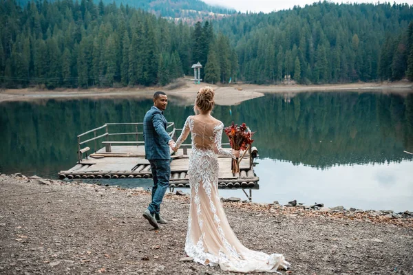 Beautiful wedding couple bride and groom at wedding ceremony on the beautiful lake background. Happy marriage couple. Loving man and woman at marriage day.