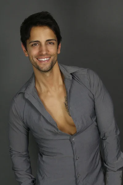 Hombre guapo con una camisa gris sonriendo — Foto de Stock