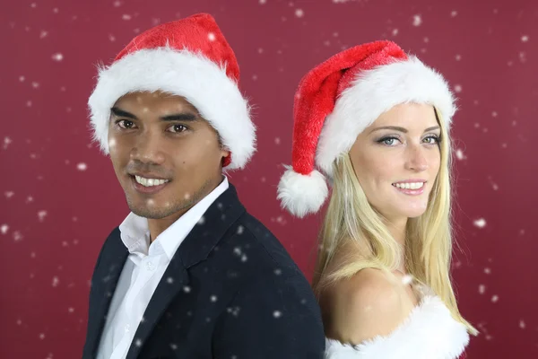 年轻混合对夫妇身穿圣诞老人的帽子 — 图库照片