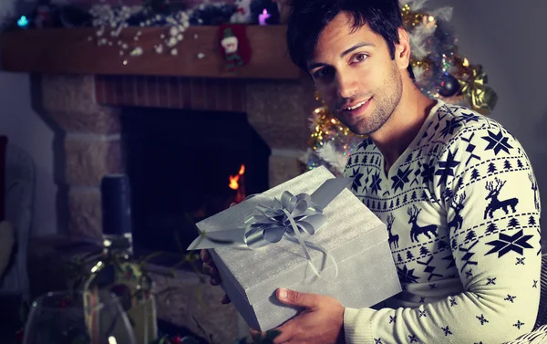 Handsome man holding a Christmas present at home — Φωτογραφία Αρχείου
