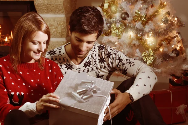 Jeune couple ouvrant un cadeau de Noël — Photo