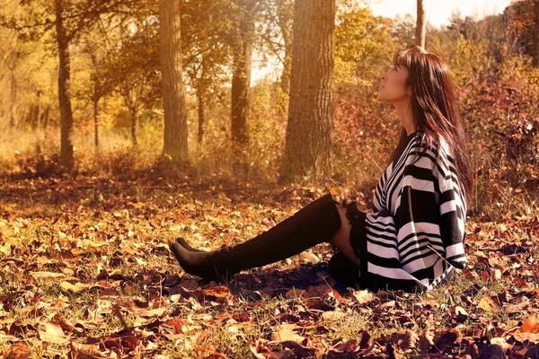 Jonge mode vrouw zitten in de herfst bladeren — Stockfoto